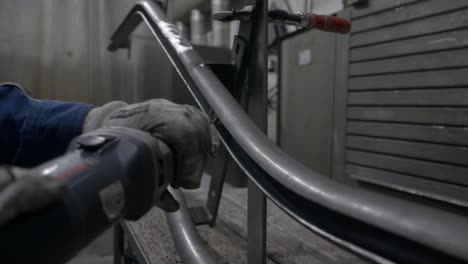 Polishing-Inside-Part-Of-Curved-Metal-Pipe-With-A-Small-Handheld-Electric-Grinder---close-up