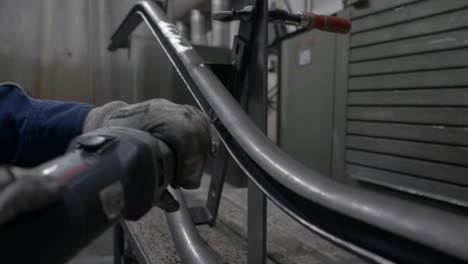 pulir la parte interior de un tubo de metal curvo con un pequeño molinillo eléctrico de mano - cerrar