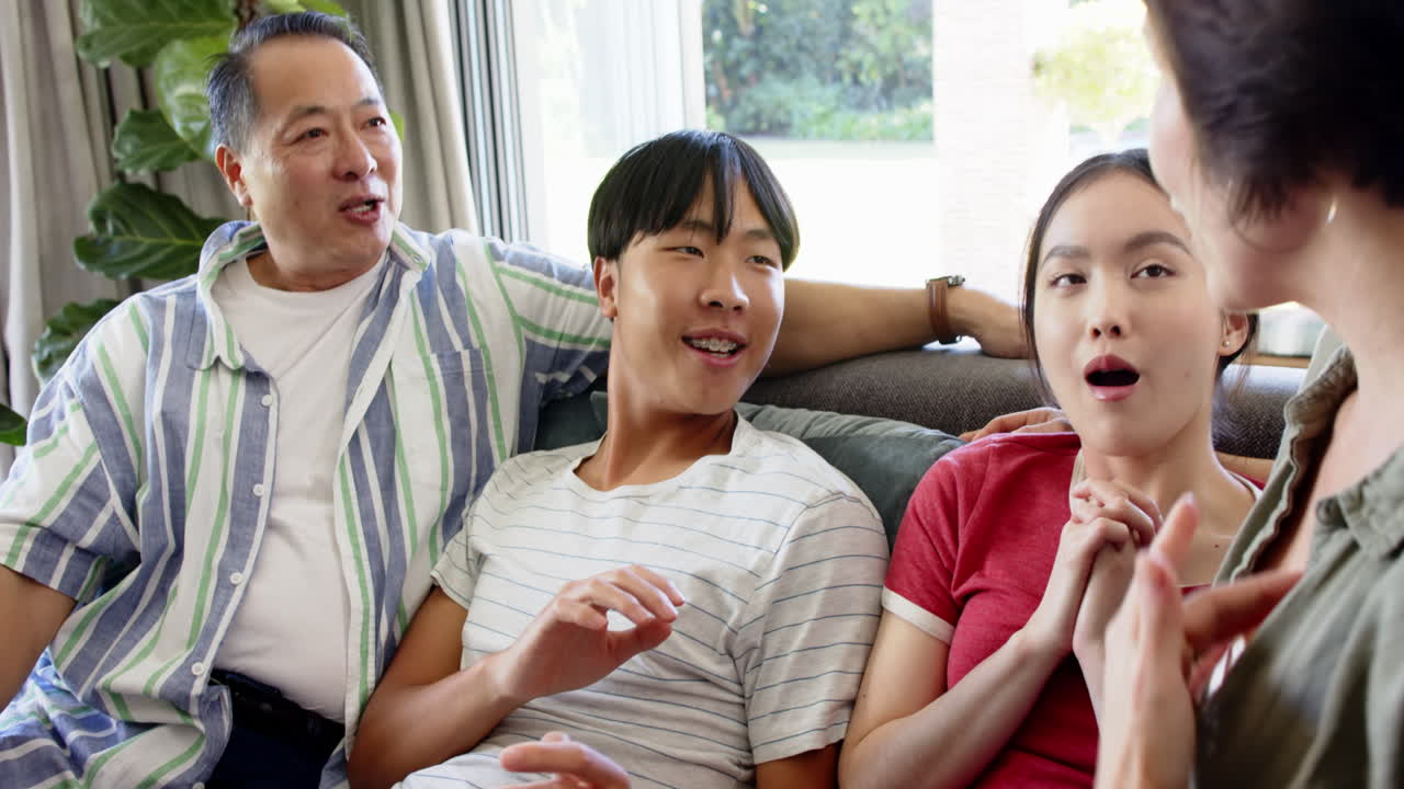 Laughing and talking, family sitting together on couch enjoying time indoors
