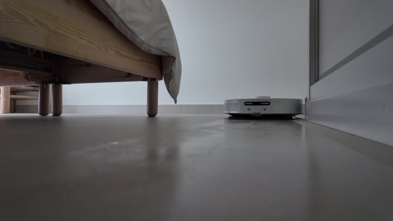 Slow-motion shot of a cleaning robot moving under a bed