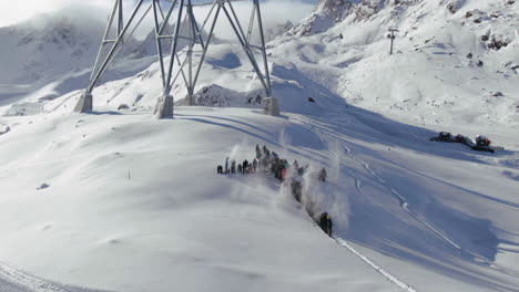 aerial pan backward movement shot of ski area in kauntertal austria with christian cross of people celebrating throwing snow up on the mountainside during winter season