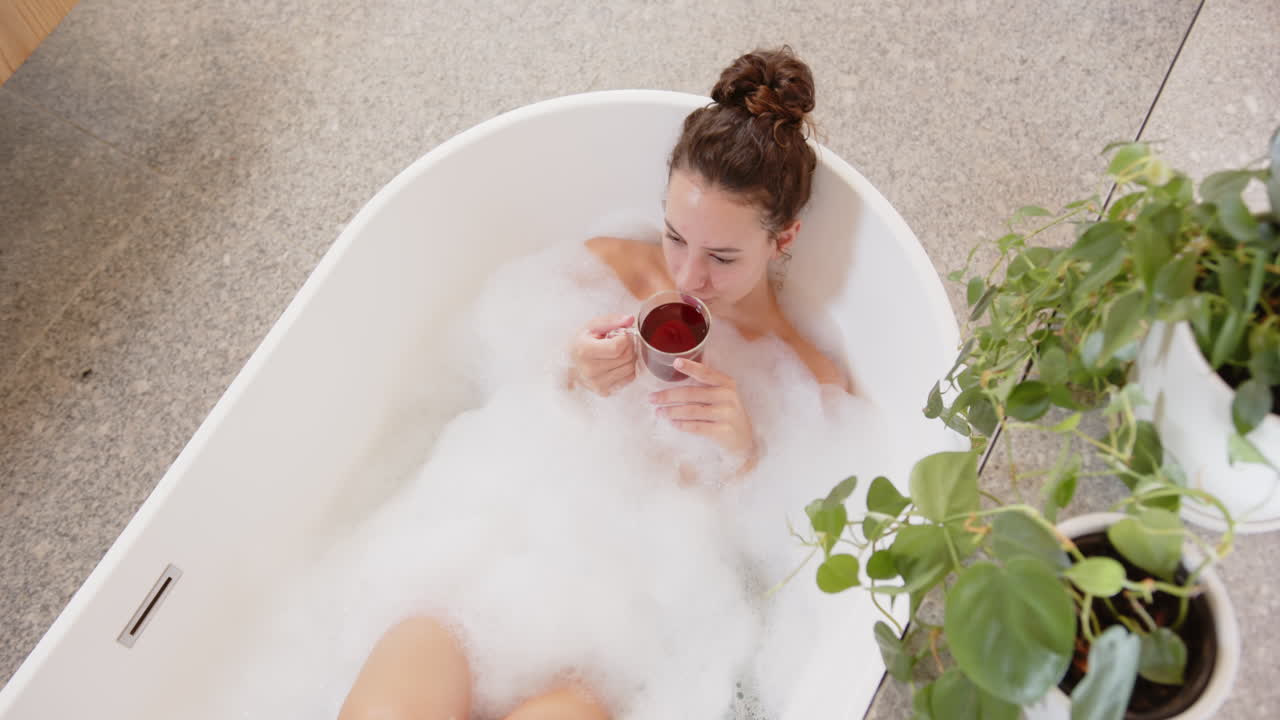 Relaxing in bathtub, woman enjoying bubble bath and drinking tea