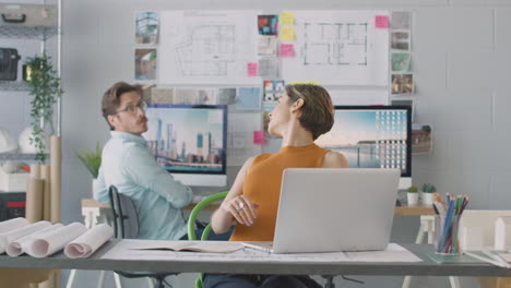 arquitectos masculinos y femeninos en la oficina trabajando en escritorios en computadoras uniéndose para reunirse juntos