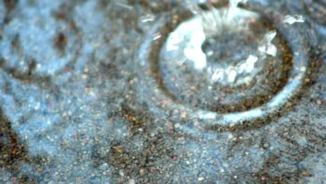 raindrops fall into water on concrete road and splashes