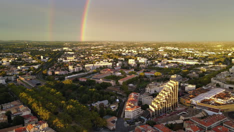 golden-hour cityscape of montpellier, punctuated by the arc of a radiant rainbow