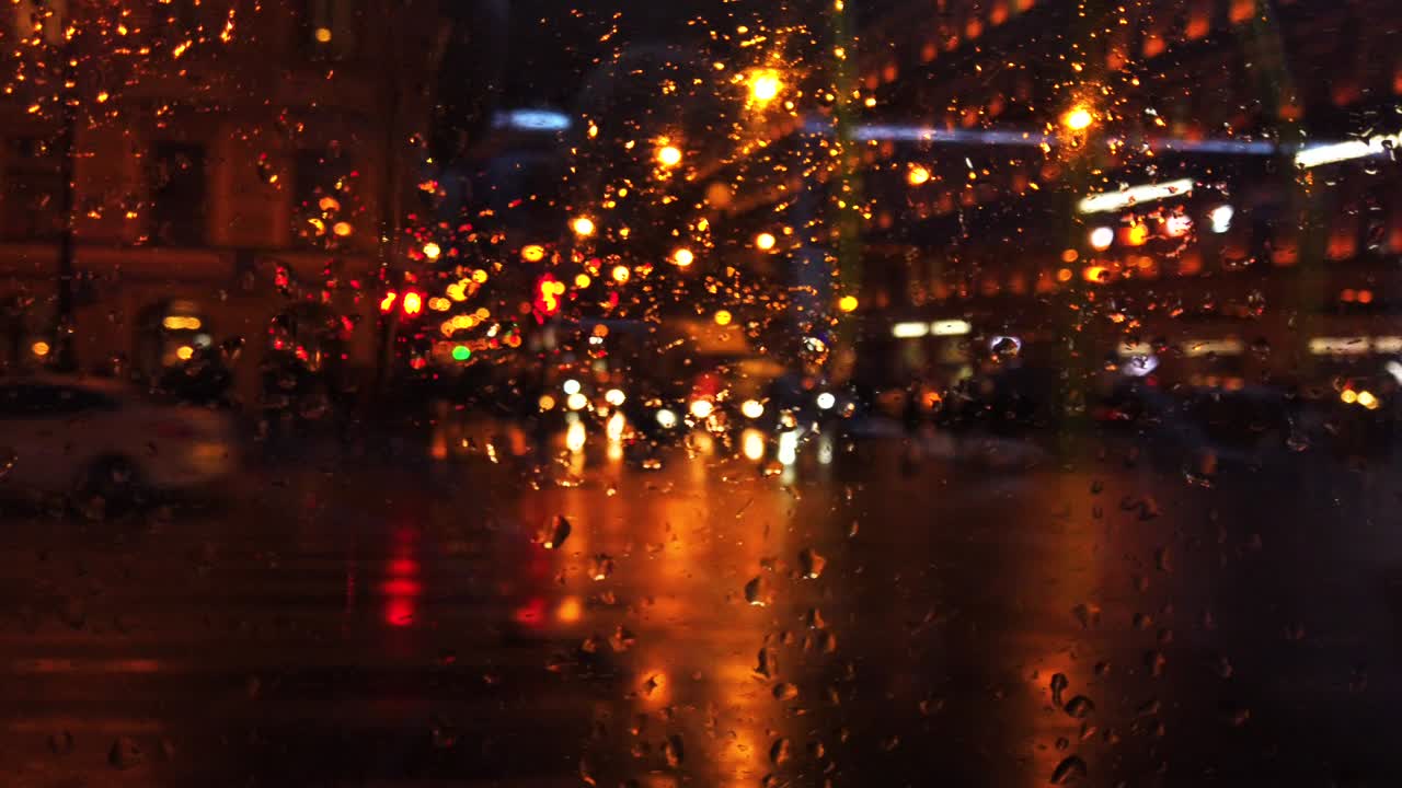 비가 내리는 동안 밤의 도시 거리에서 초점을 맞추지 않은 불빛