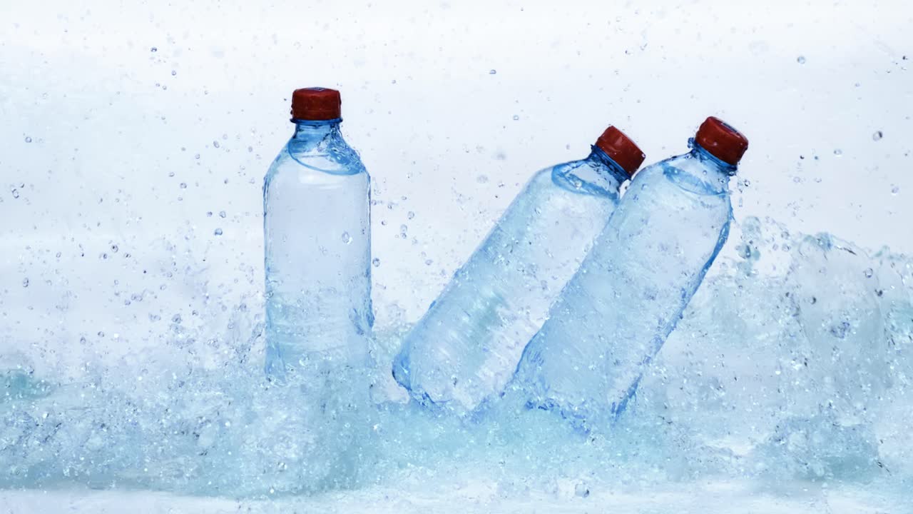 botellas de agua potable fresca en agua azul salpicada. filmado con una cámara súper lenta de 1000 fps.
