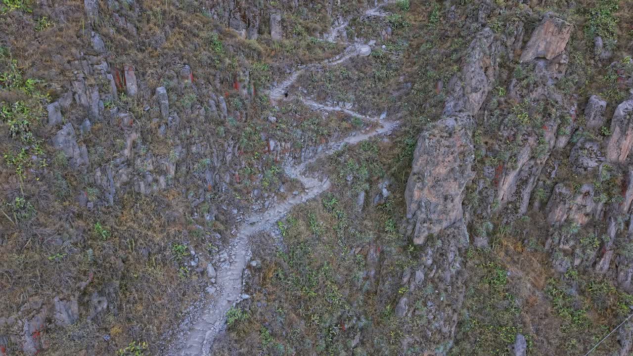 Drone approaches the iconic zigzag hiking trail as a young female traveler descends into Famous Colca Canyon, surrounded by rugged terrain and remote, dramatic landscape