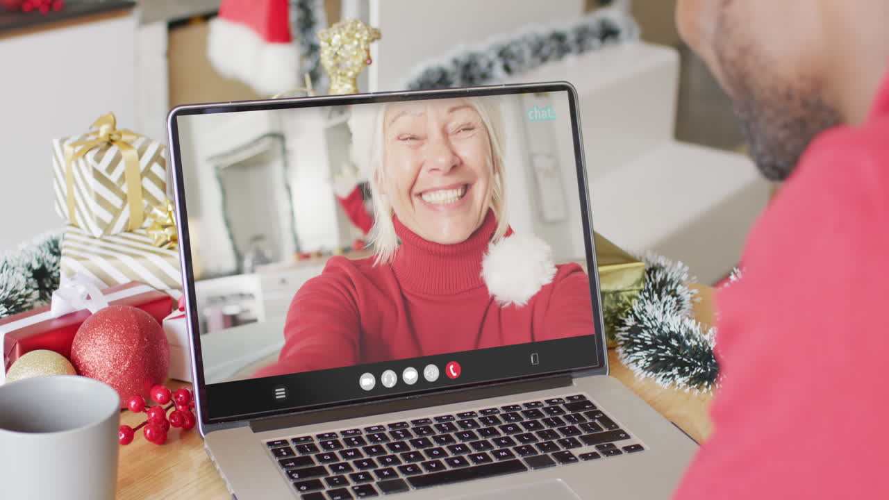hombre afroamericano con decoraciones de navidad haciendo una llamada de video con una mujer caucásica