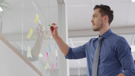 Hombre-De-Negocios-Caucásico-Tomando-Notas-Sobre-La-Pared-De-Vidrio-En-La-Oficina,-Cámara-Lenta