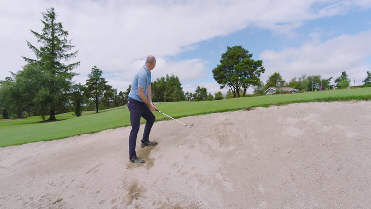 Giocatore di golf maschio che gioca a golf e colpisce la pallina da golf sul campo da golf