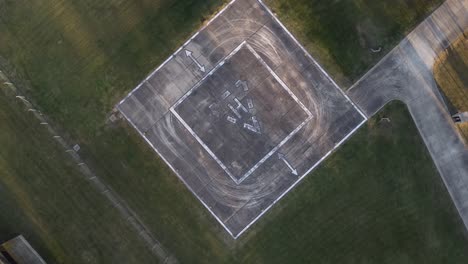 aerial drone top down circling view of empty heliport for helicopter in green meadow