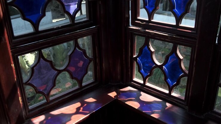 La luce del sole filtra attraverso le ornate vetrate artistiche blu e viola di una struttura tradizionale cinese