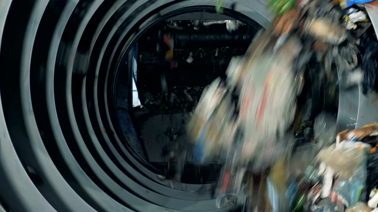 기계적 쓰레기 분류 과정: 쓰레기는 컨베이어에서 분류를 위해 회전하는 기계에 떨어집니다.