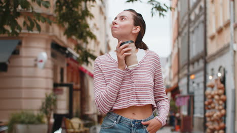 happy smiling woman walking on city street enjoying morning coffee hot drink relaxing taking a break