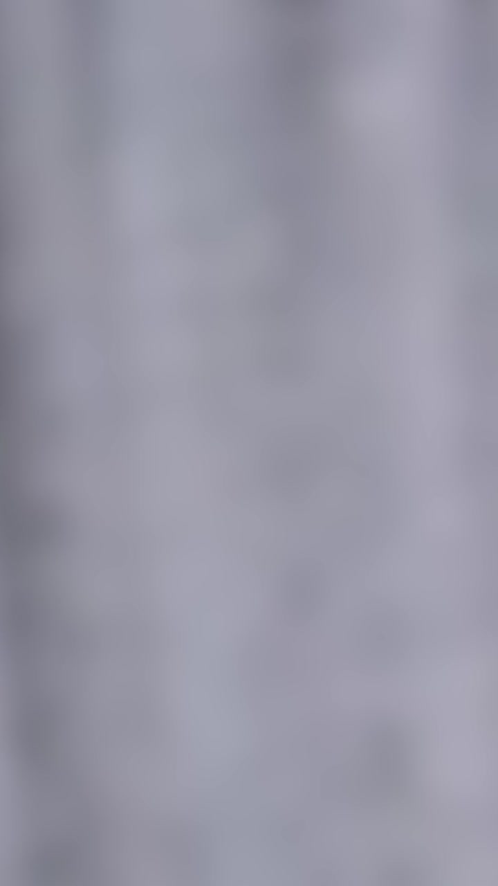 Blurred vertical lines suggest motion, resembling falling smoke or clouds with a soft, muted color palette