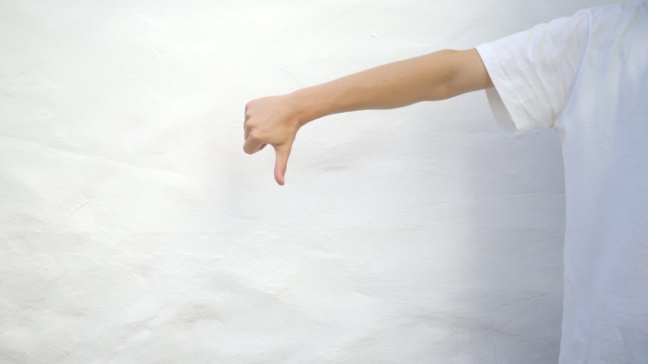 흰색 티셔츠를 입은 남자는 엄지손가락을 위로, 엄지손가락을 아래로 내립니다.