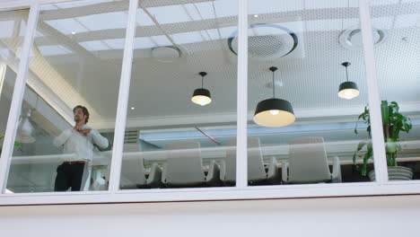 hombre de negocios exitoso mirando por la ventana de la oficina sonriendo confiado con los brazos cruzados disfrutando del liderazgo corporativo joven hombre ejecutivo planeando hacia adelante para un futuro positivo imágenes de 4k