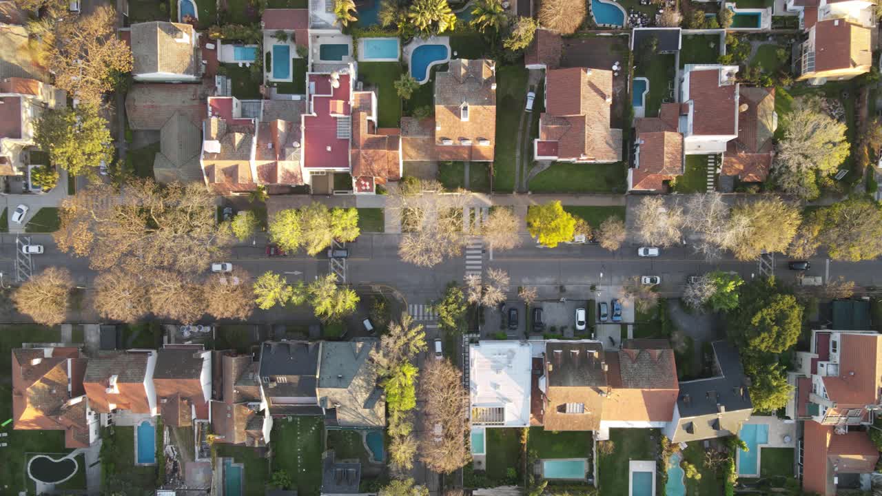 tiro de lapso de tiempo de la zona residencial con coches de conducción en la carretera durante la puesta de sol en buenos aires, argentina - árboles otoñales y piscinas en el distrito de lujo
