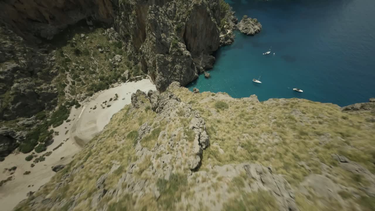 un dron fpv disparó cuesta abajo sobre un terreno montañoso en torrent de pareis a lo largo del área de la bahía en sa calobra, mallorca, españa en un día soleado