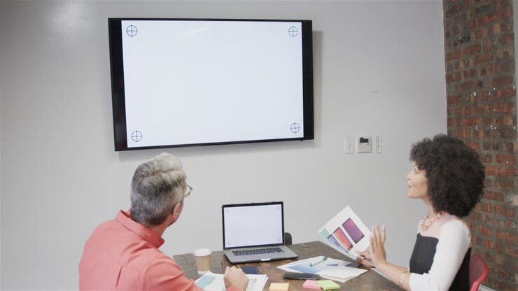 Diverse colleagues having video call with laptop and monitor, copy space on screens, slow motion