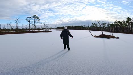 action cam follows woman skating across snowy bog lake at sunrise in latvian