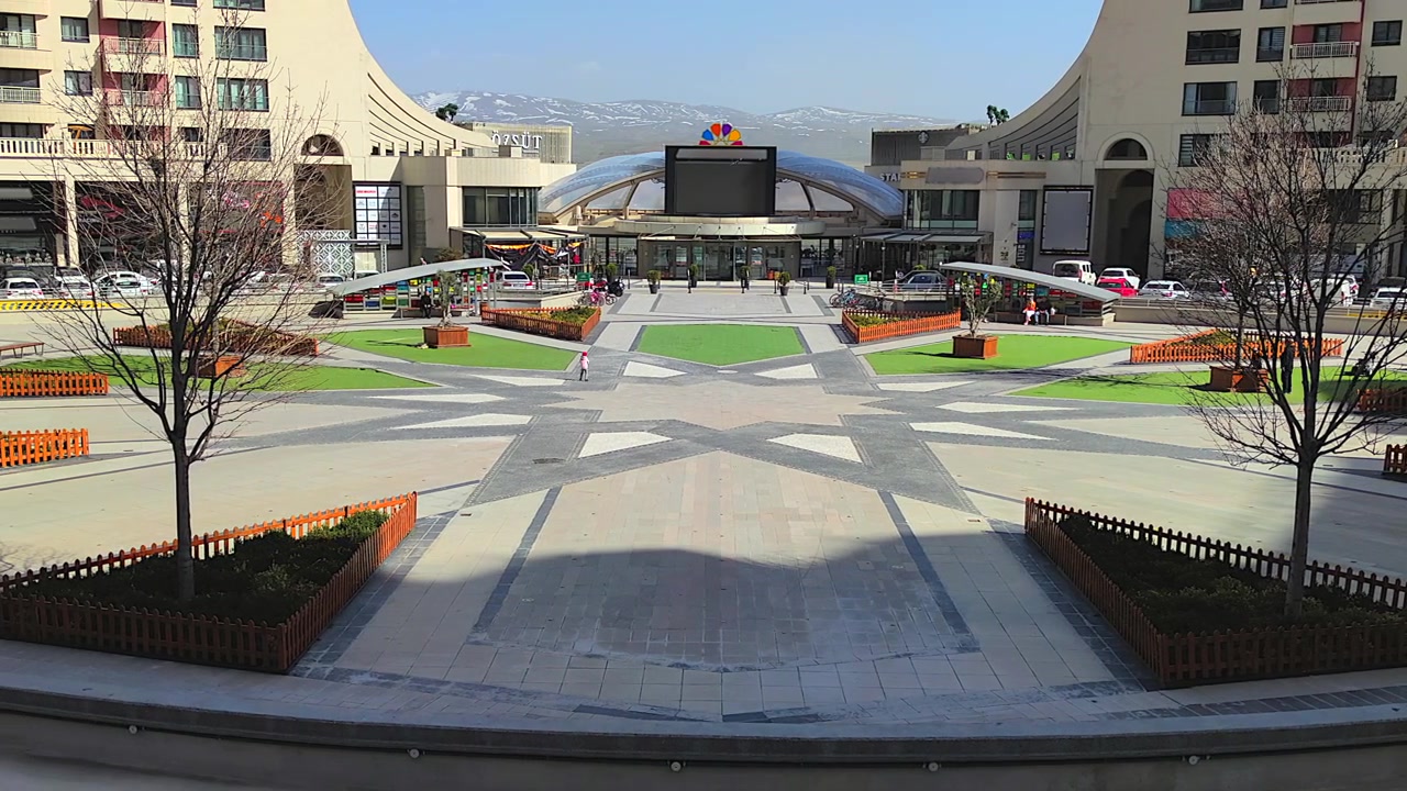 Pessoas caminhando em praça urbana moderna com shopping center