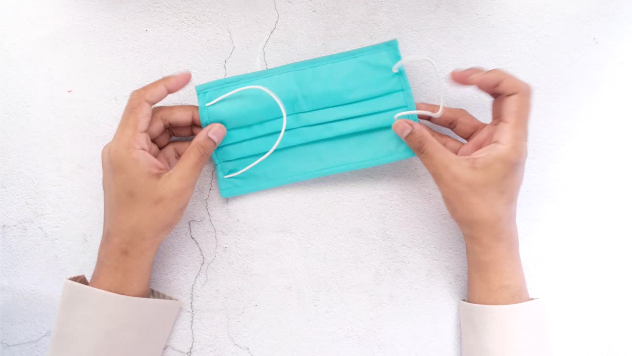 밝은 푸른색 얼굴 마스크를 들고 있는 사람