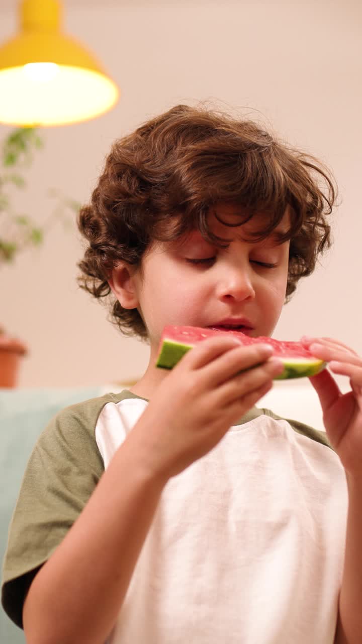 Young boy eating watermelon slice by slice