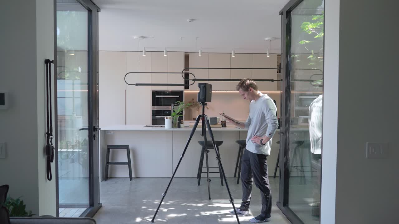 현대 가정의 매터포트 장치를 향해 걸어가는 평면도 전문가의 넓은 샷, 측정 장비