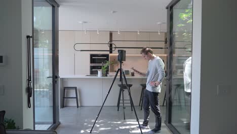 wide shot of floor plan specialist walking towards matterport device in modern home, measuring equipment