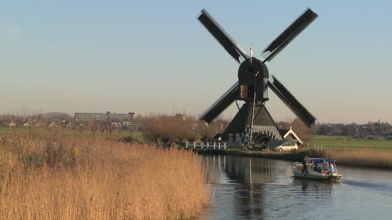 лодка движется по каналу в голландии с ветряными мельницами поблизости 7