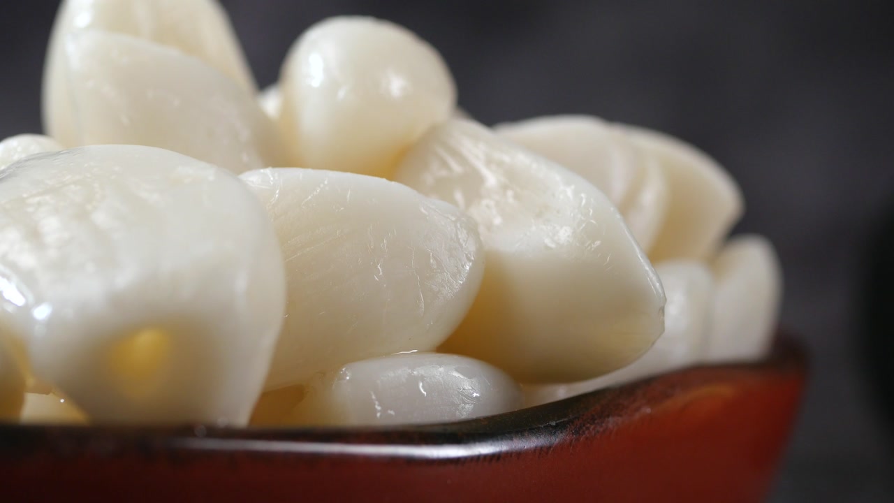 Close-up of Pickled Garlic Cloves in a Brown Bowl