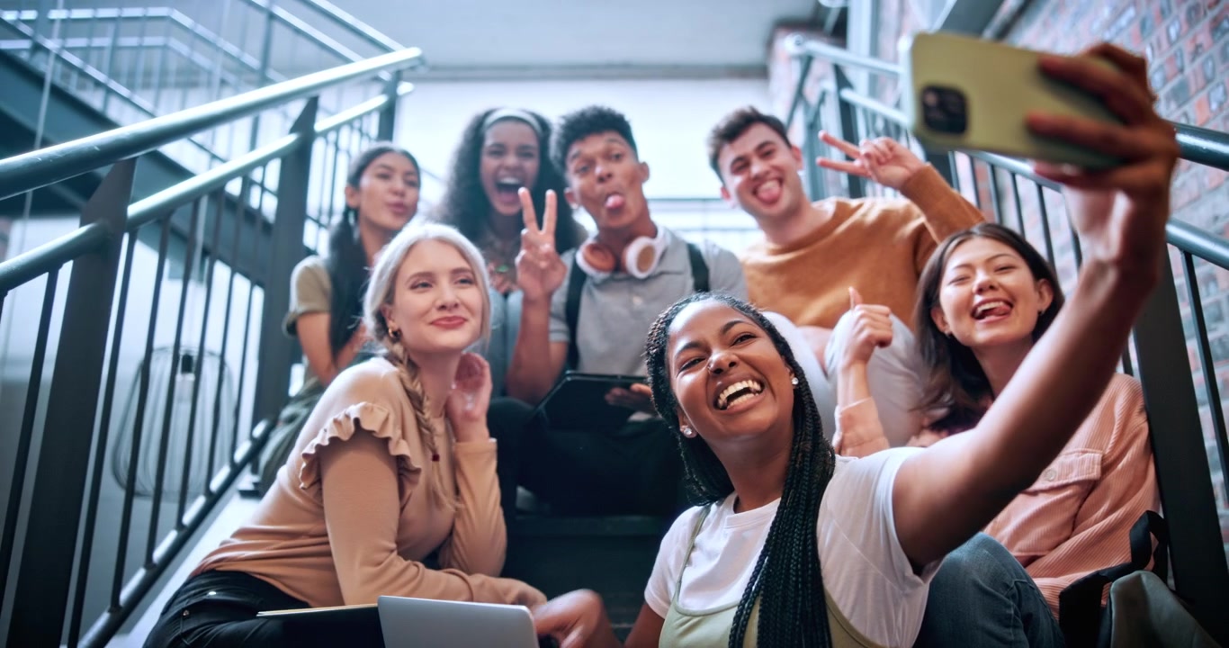 Gruppo eterogeneo di studenti che si scattano un selfie sulle scale