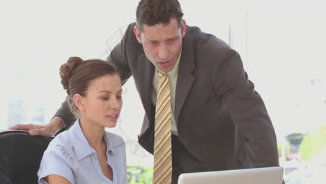 in office, businessman in suit explaining animation project to woman at desk