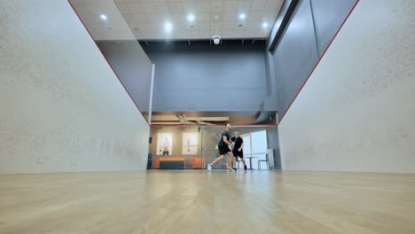 intense indoor squash game with low angle showing footwork and momentum