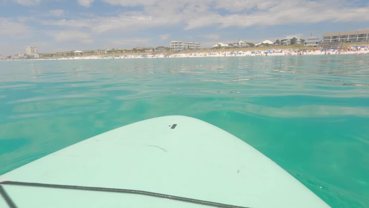 tabla de remo flotando frente a la costa de miramar beach, florida, en el golfo de méxico.