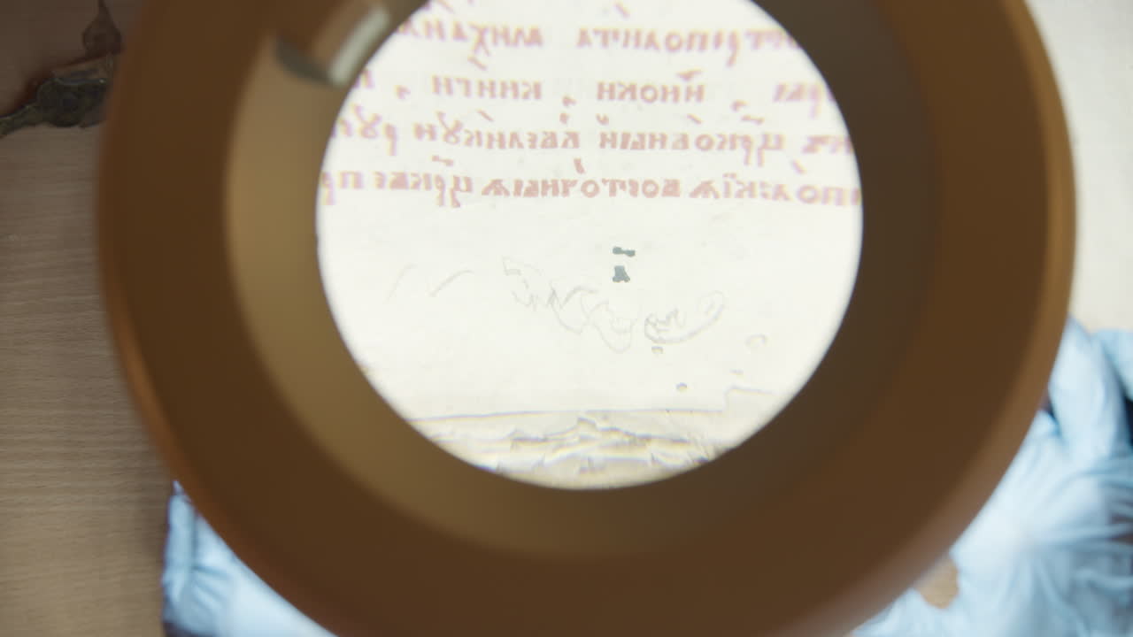 анализирует древний рукопись с помощью увеличительного стекла