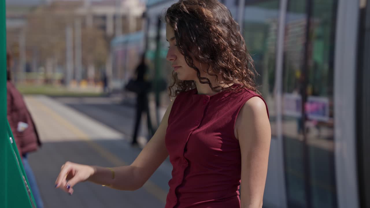 Giovane donna che acquista un biglietto in una stazione dei trasporti pubblici
