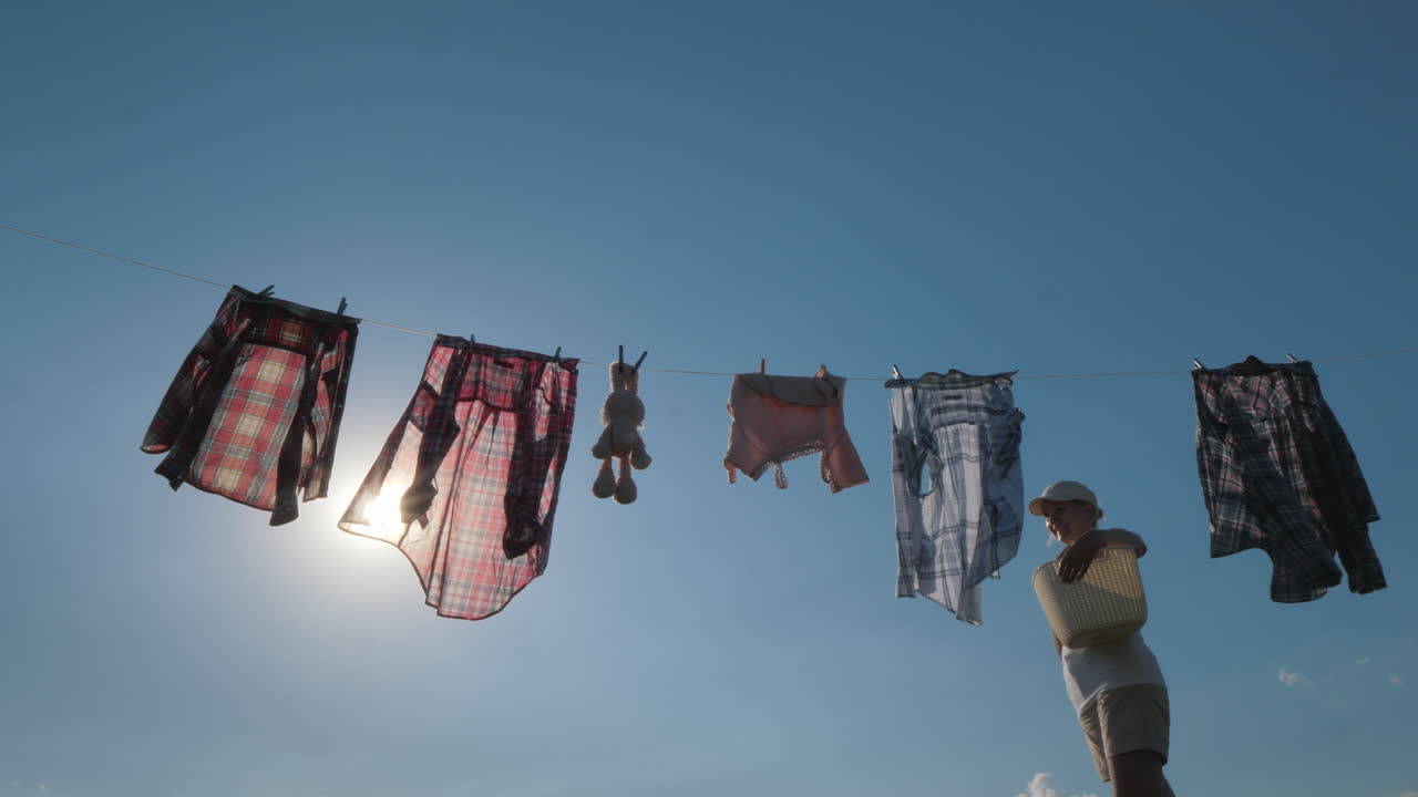 una mujer con una canasta parece colgar ropa mojada en una cuerda video 4k