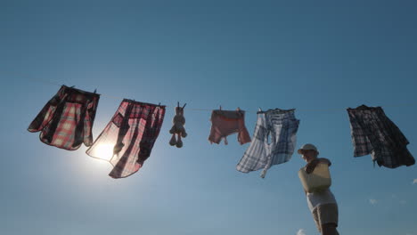 a woman with a basket looks like hanging wet clothes on a rope 4k video