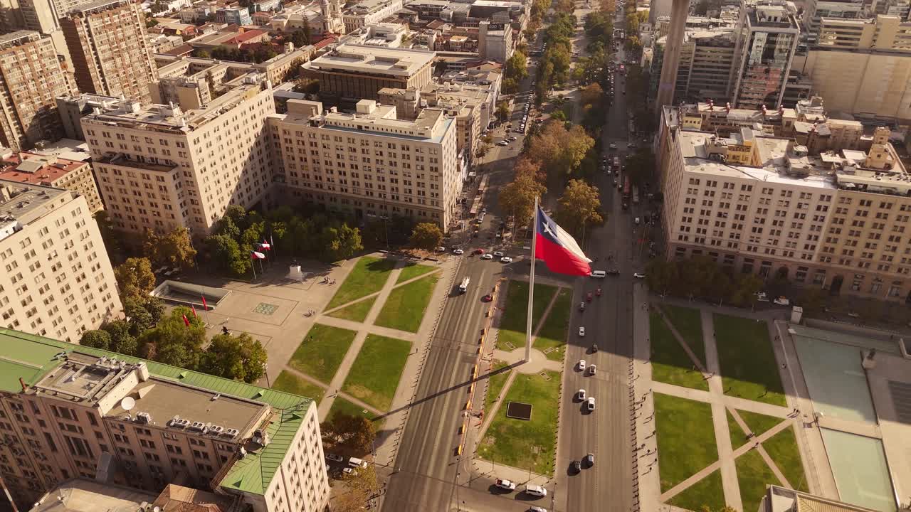 Aerial of the Bandera Bicentenario, a massive Chilean flag waving proudly along a busy avenue in de Chile, along with city traffic.
