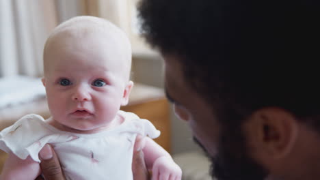 loving father playing with smiling baby daughter at home