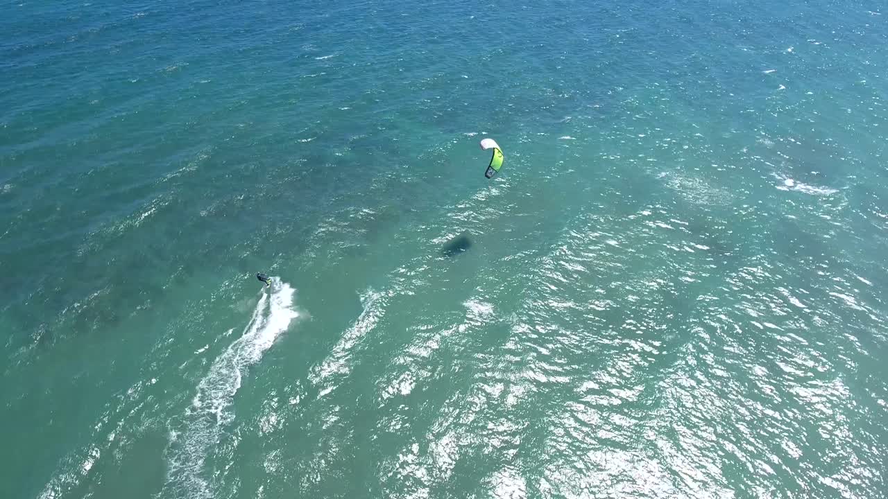 imágenes de drones de kitesurfistas a vista de pájaro navegando sobre océano abierto