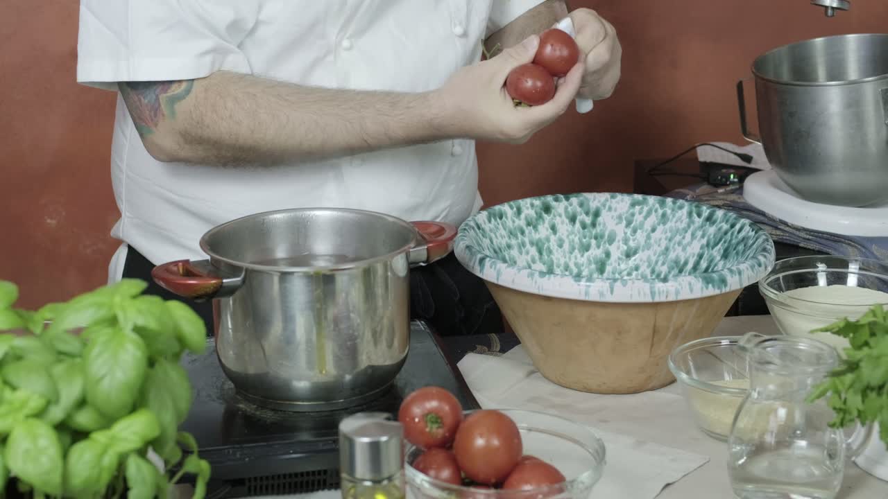 el chef corta la piel alrededor de tomates pequeños y los coloca en agua hirviendo para hacer pesto casero