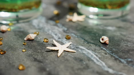 natural color star-like decorating material placed near transparent tealight cups filled with green wax mixture and fixed wick, set on smooth kitchen countertop under warm indoor lighting