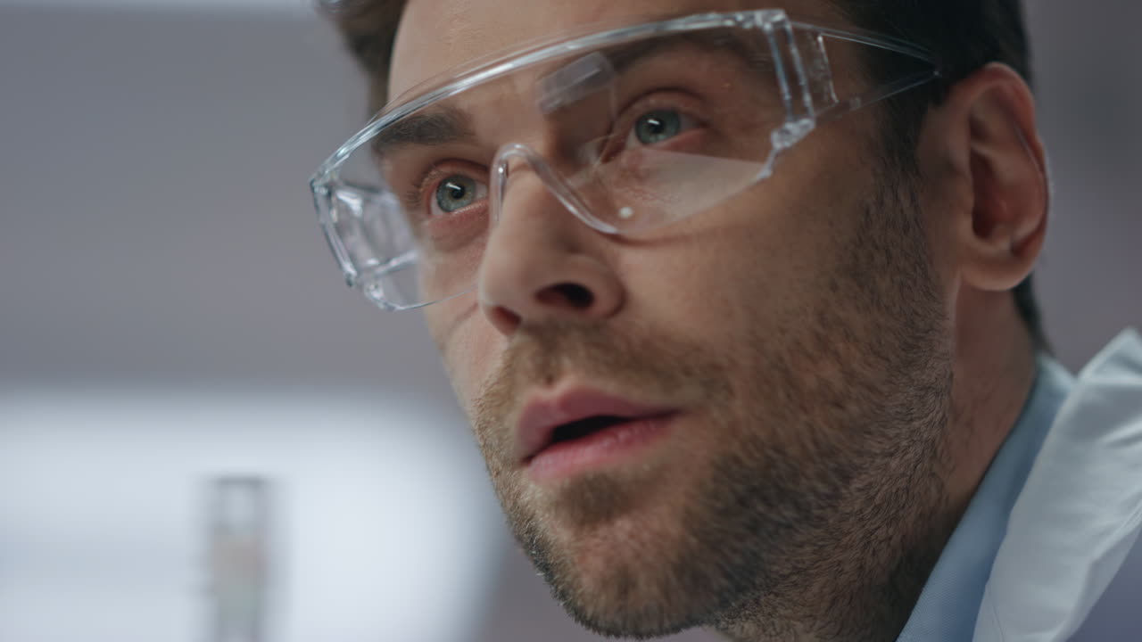 científico experto en primer plano mirando un tubo de ensayo con preparación médica en el laboratorio.