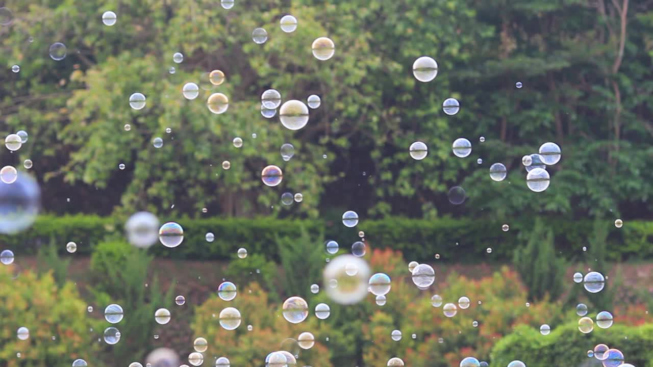 어린이와 어린이를 위한 자연 녹색 흐릿한 보케 배경으로 공중에 떠다니는 비누 거품