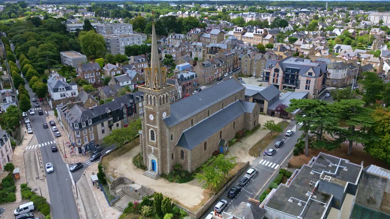 A drone panning shot captures Notre-Dame d’Émeraude Church in Dinard, with surrounding streets, houses, and urban buildings visible in detail