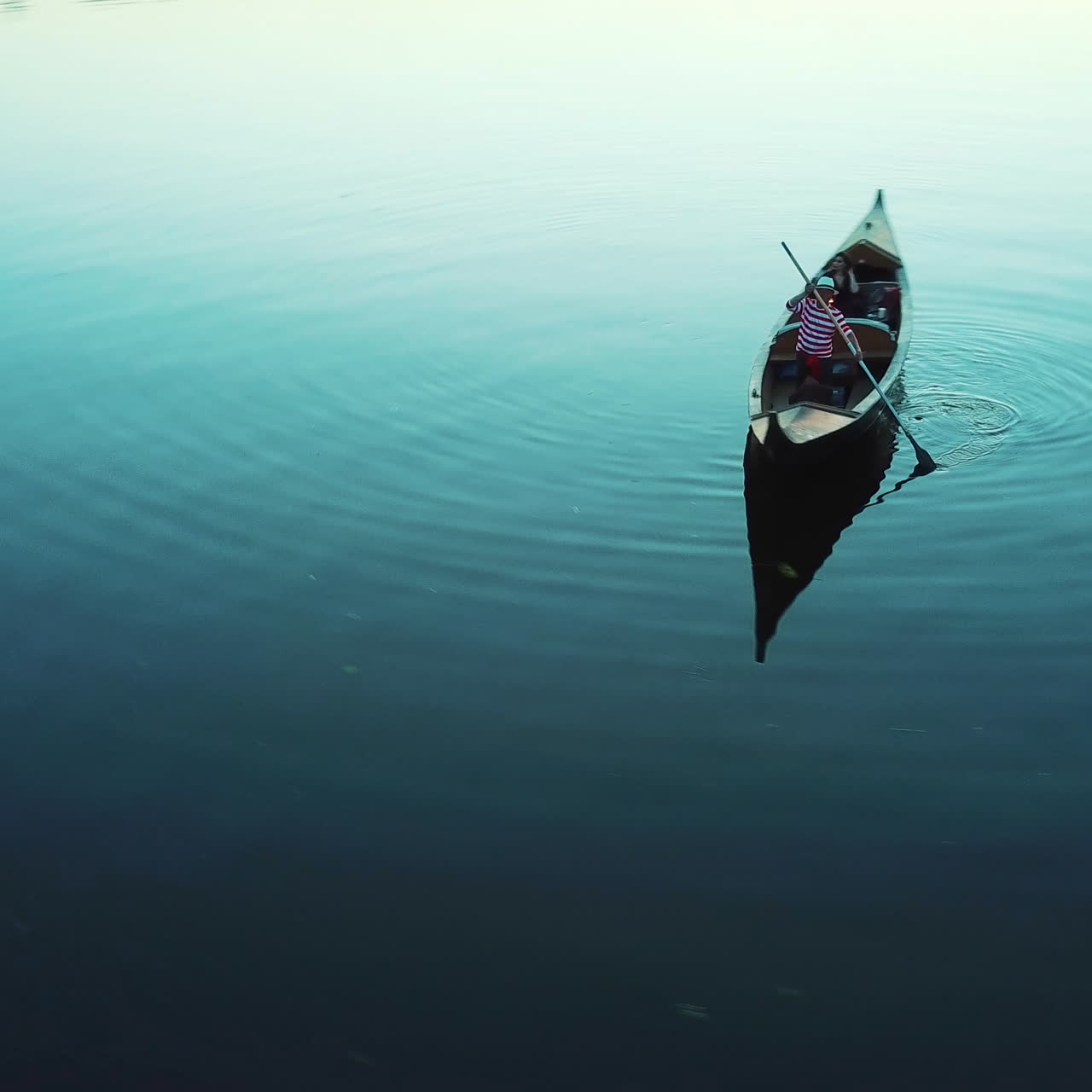 Woman and a gondolier floating in a boat on the evening river. Man in white hat and striped shirt carring elegant woman with lantern in a boat. Quick aerial view around.